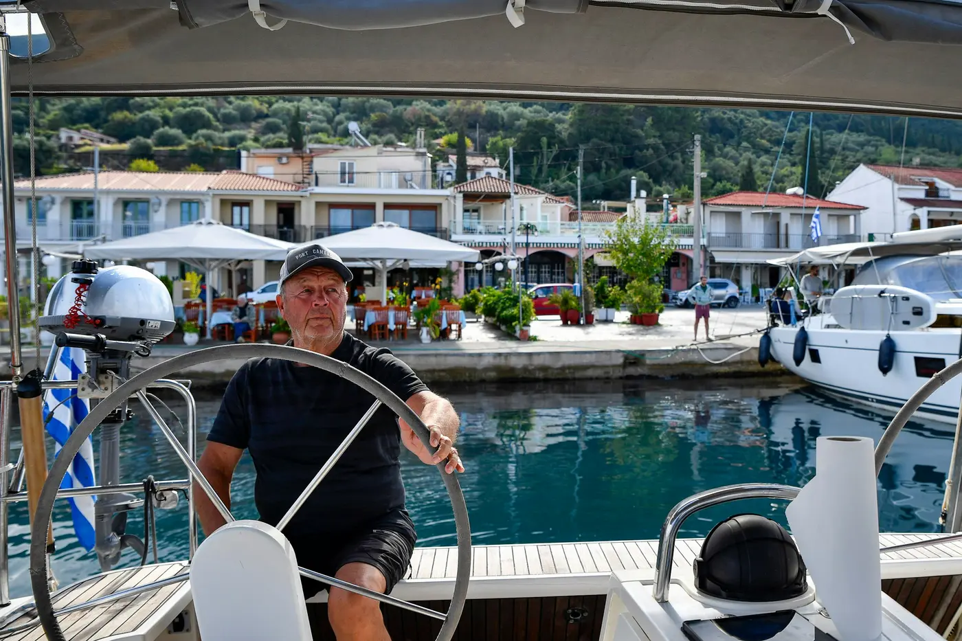 A smiling captain at the wheel of a boat in a harbor