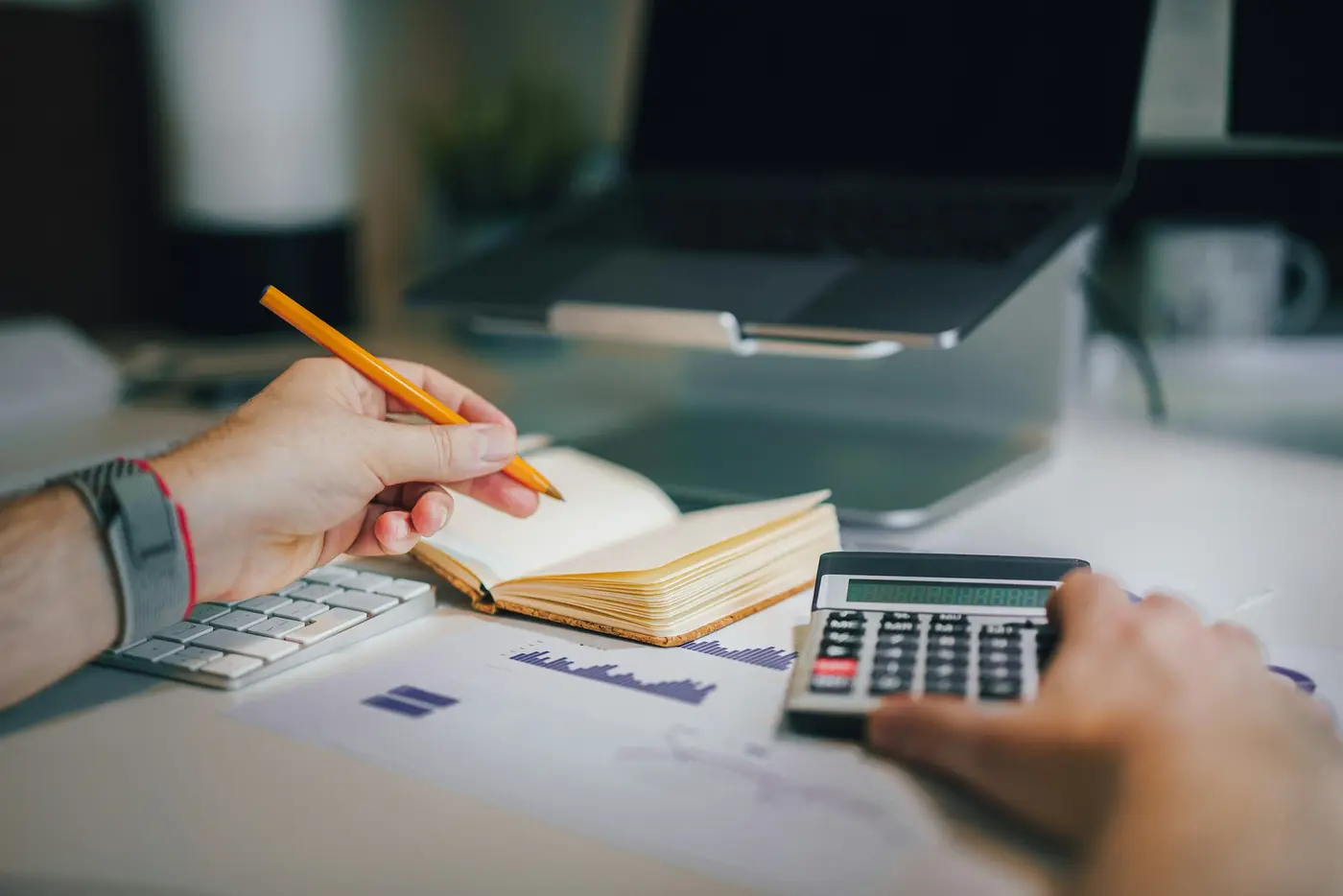 A person working through figures with a notebook and calculator