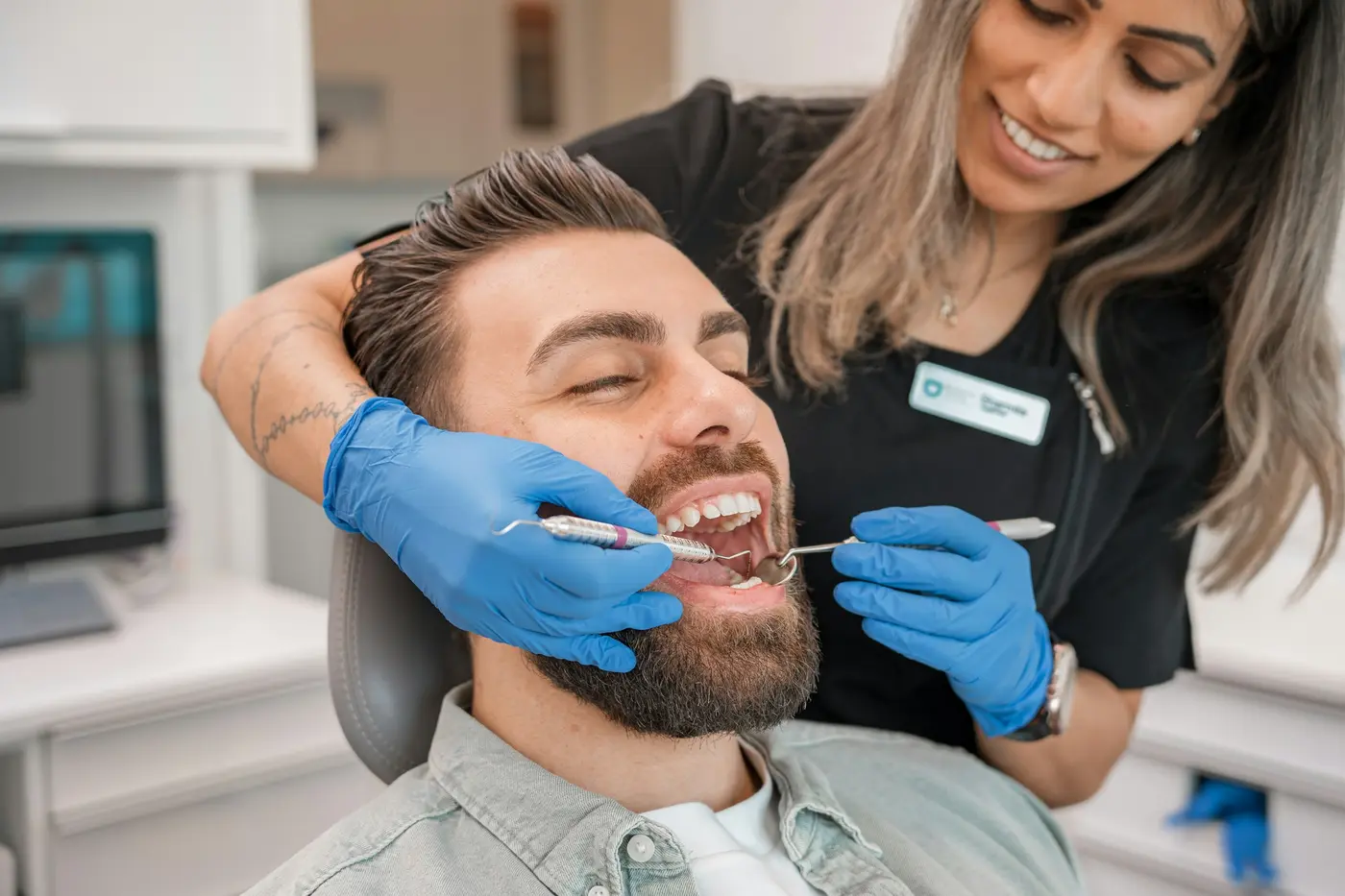 A dental professional and a smiling patient in the chair