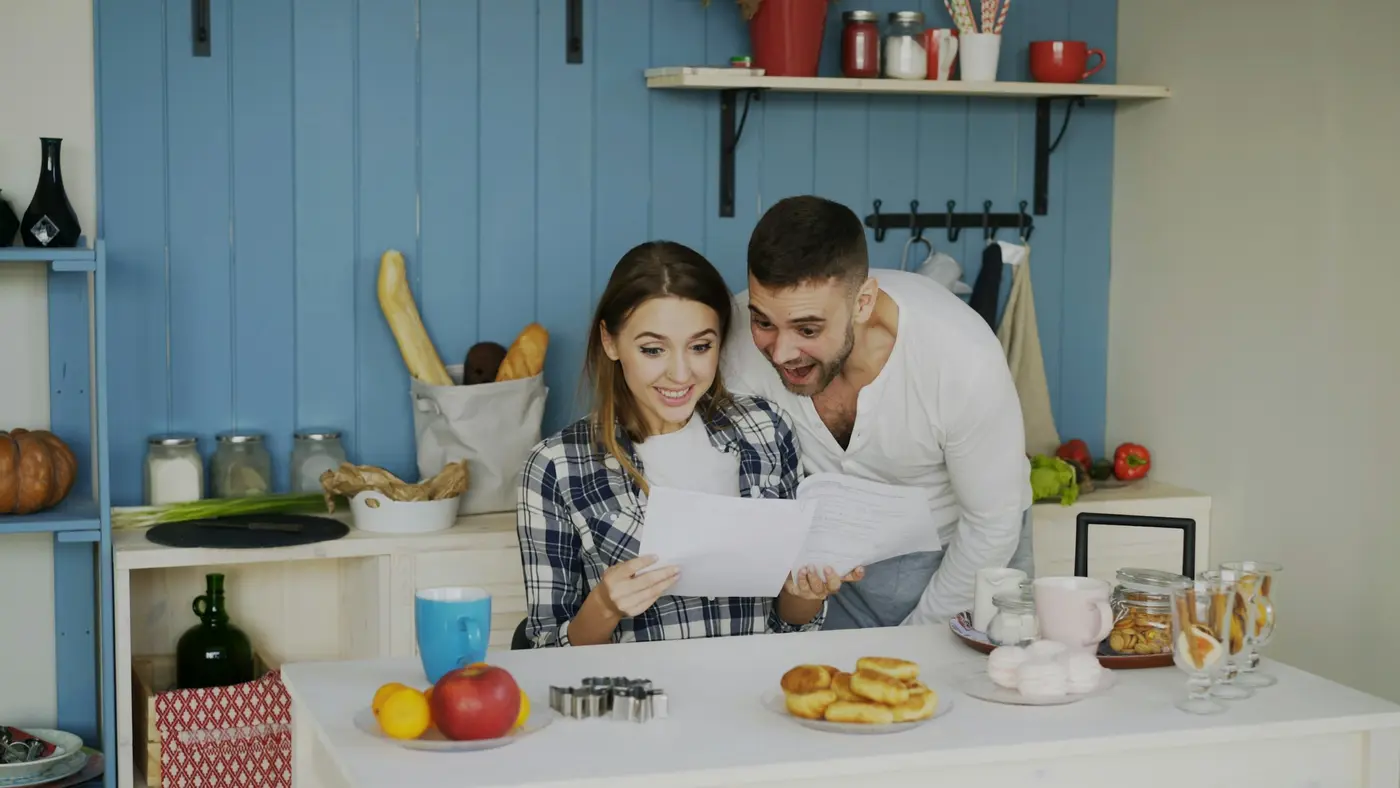 A couple reading through paperwork together in a bright kitchen